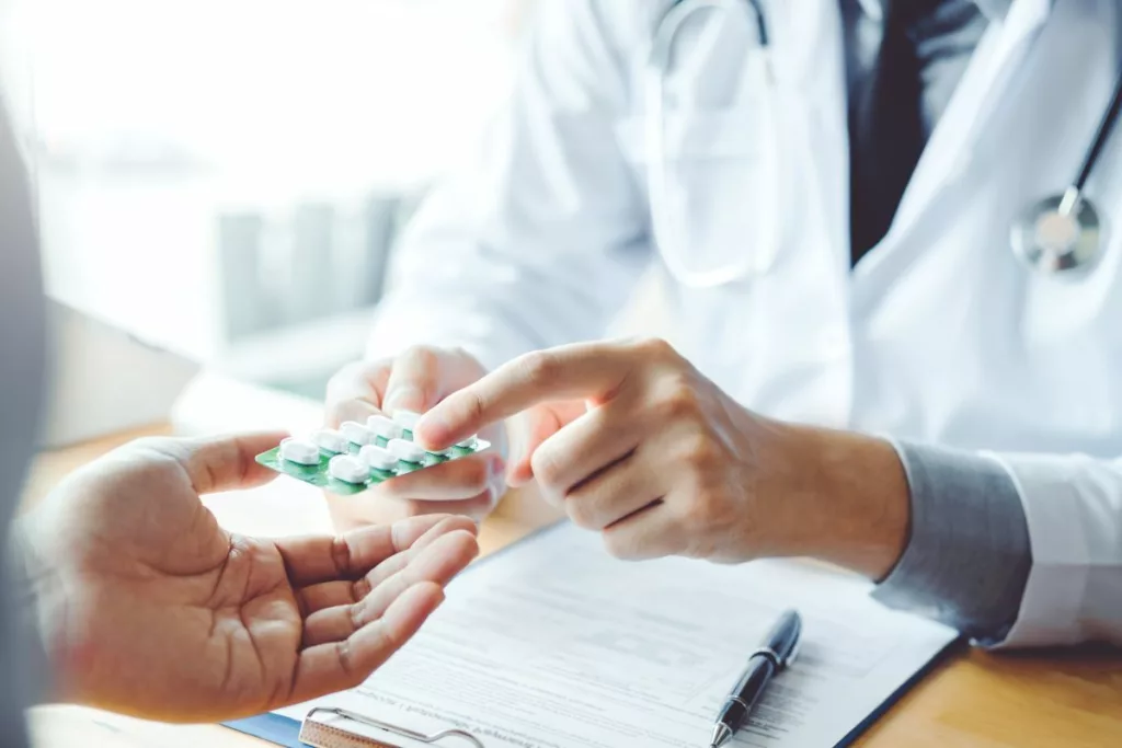 Doctor providing medication to patient, with free NHS prescriptions.