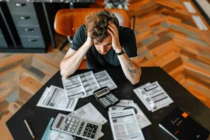 A man at a desk, engaged with paperwork and a calculator, analysing third-party deductions.