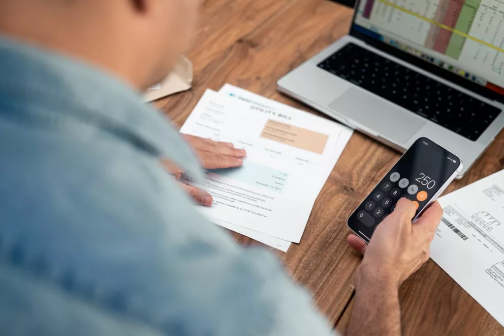 A man using a calculator to check the cost of his energy bills and get an an energy bill payment plan in place.